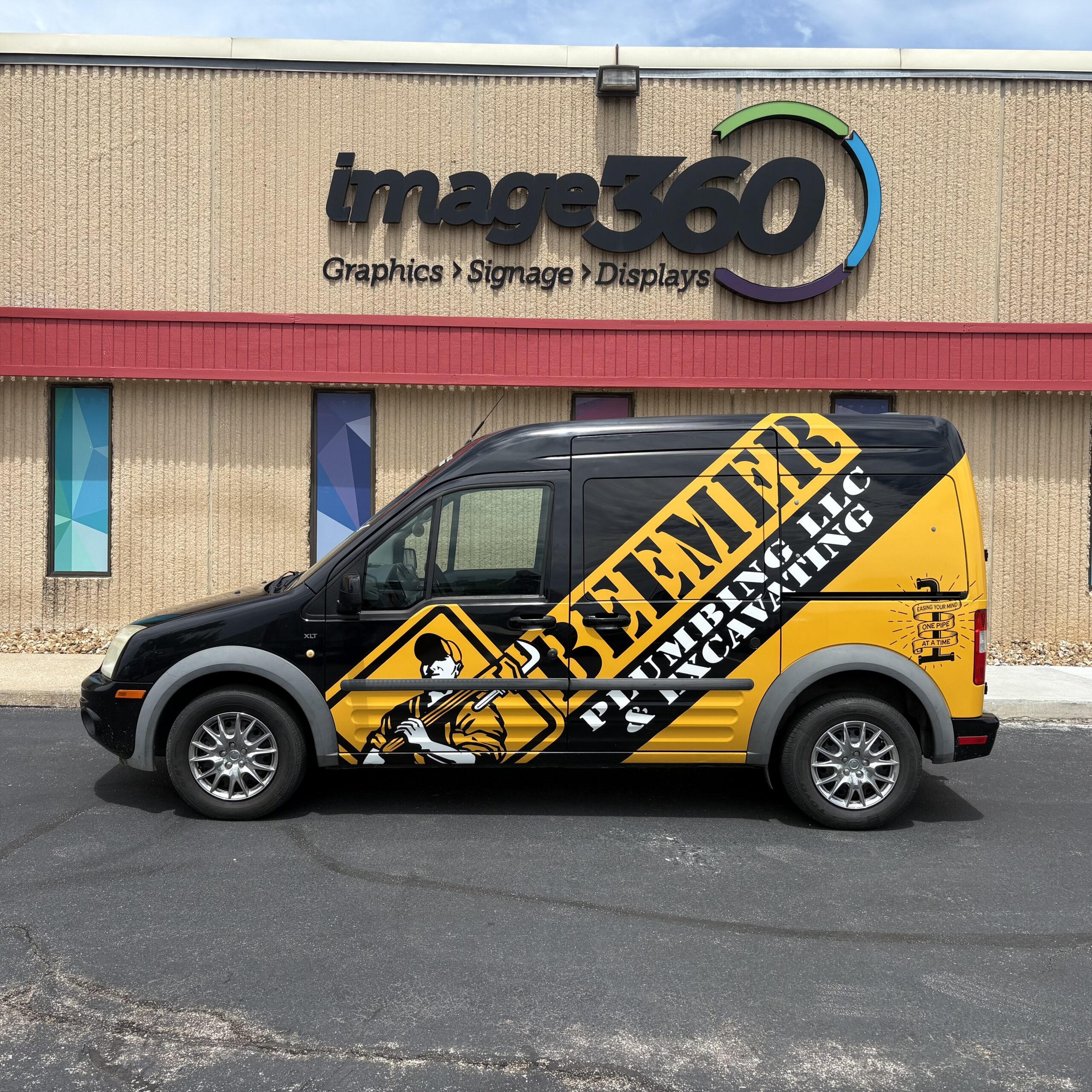 Black and yellow full vehicle wrap on a Beemer Plumbing LLC compact van in Kansas City